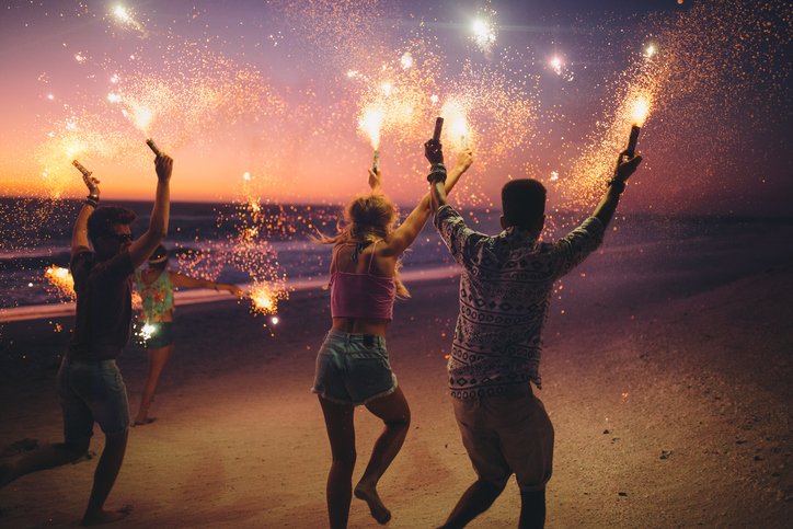 People waving sparklers on beach