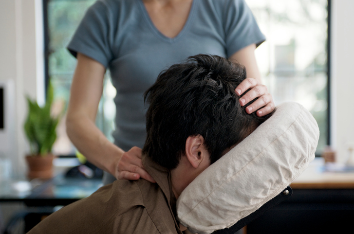 Person receives chair massage for neck injury